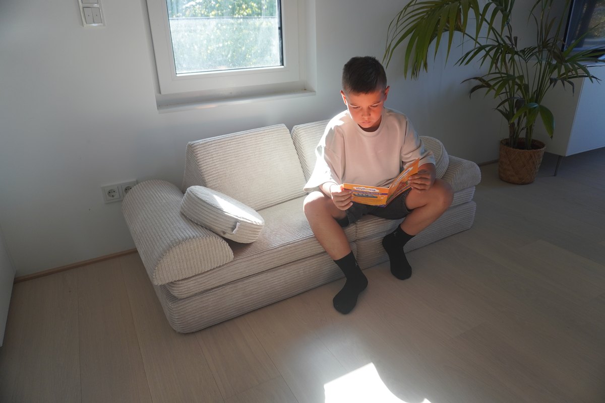 Kind liest das Linodino-Ideenheft der Fantasiewelt auf dem Spielsofa