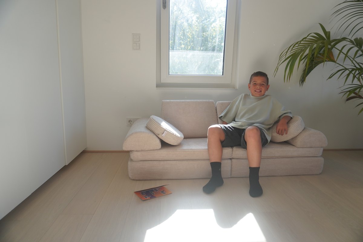 Kind lächelt auf dem Linodino Spielsofa Fantasiewelt in Beige