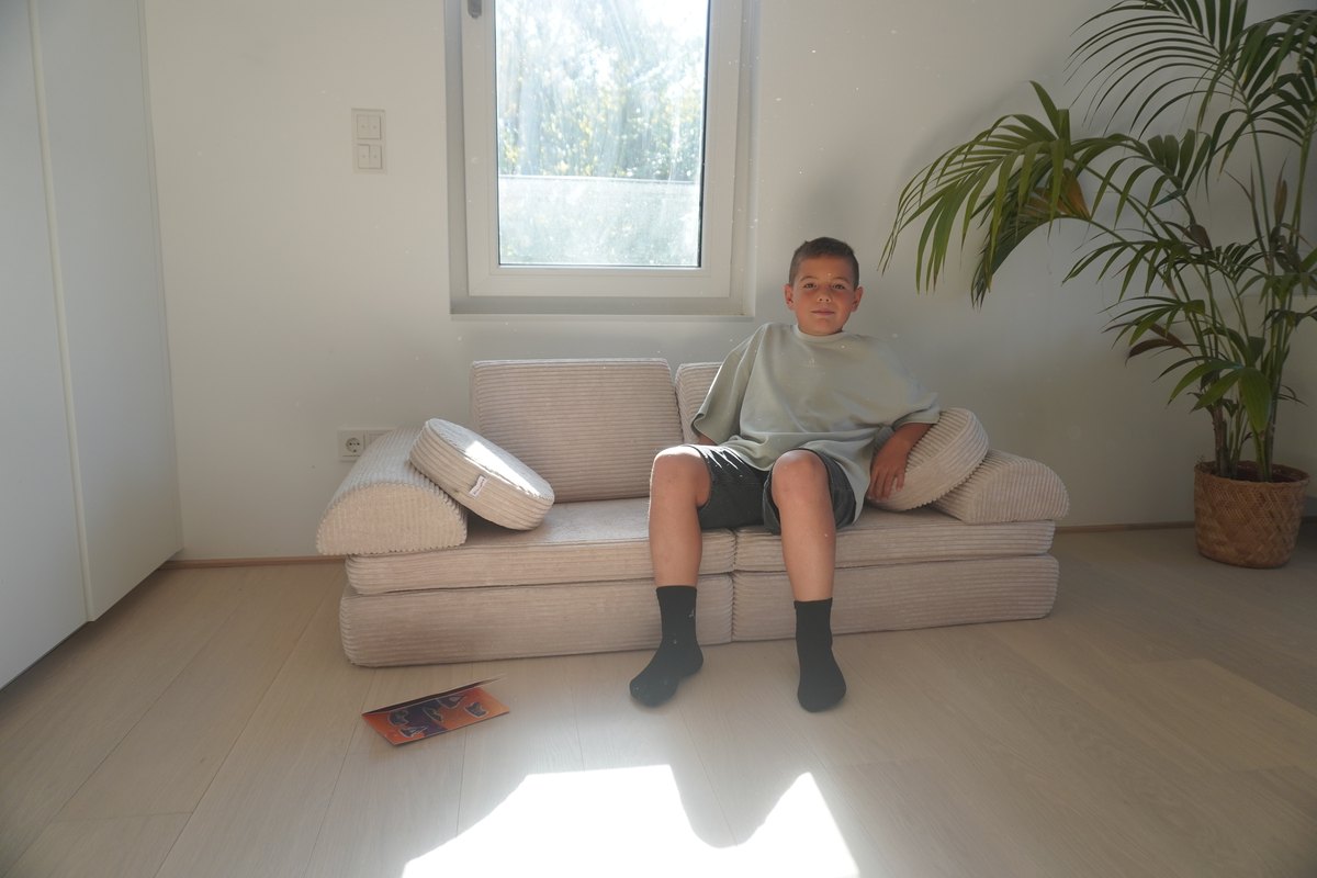 Achtjähriger sitzt auf dem Linodino Spielsofa Fantasiewelt in Elfenzauber Beige im Wohnzimmer