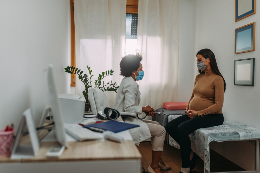 Young,Pregnant,Woman,On,A,Visit,To,Doctor.,Wearing,Protective